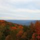 An overview of a rural West Virginia forest with red, orange, and green trees and mountains.