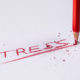 Red "Stress" written on white paper, with broken pencil in top right corner